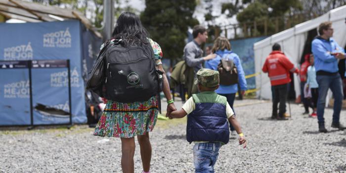 Indígena embera camina con su hijo de la mano cargando un morral en Bogotá