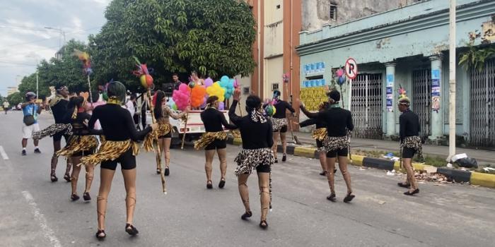 Grupos de personas haciendo presentación en desfile del mes del orgullo LGBTIQ+